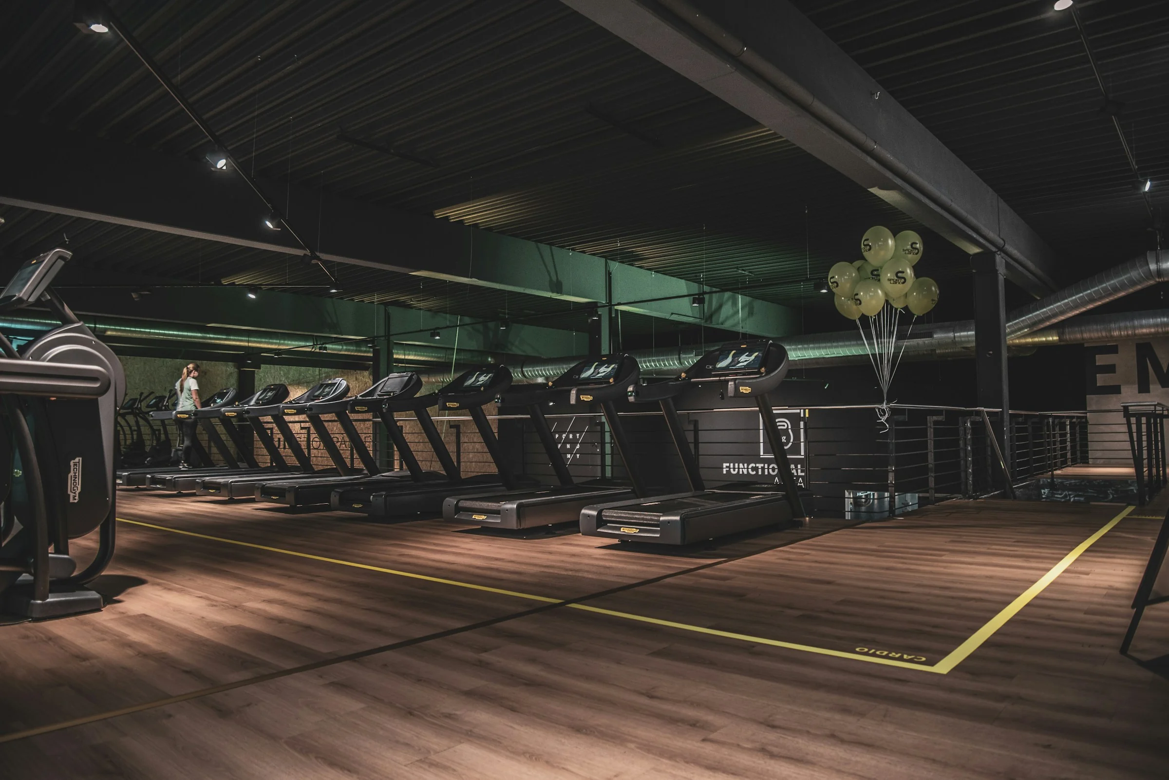 Row of treadmills in a gym with wooden flooring
